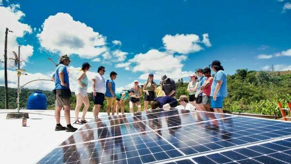 Students stand and look at solar panels